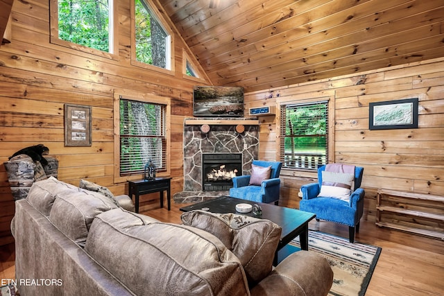 living room with wood ceiling, a stone fireplace, high vaulted ceiling, wood walls, and hardwood / wood-style flooring