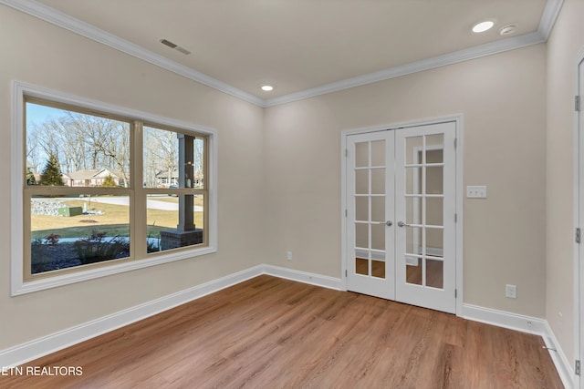 spare room featuring crown molding, light wood-type flooring, and french doors