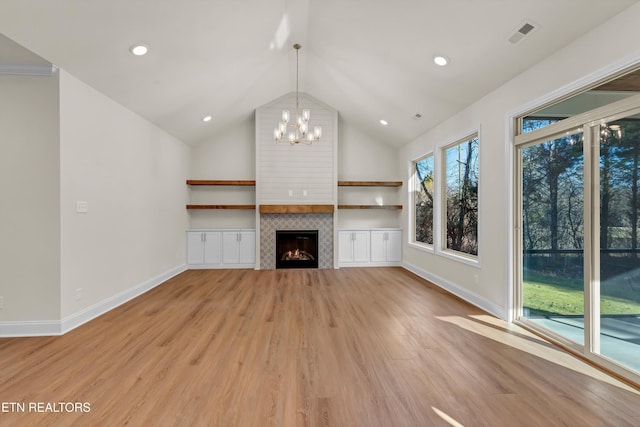 unfurnished living room featuring a chandelier, a tiled fireplace, vaulted ceiling, and light hardwood / wood-style flooring