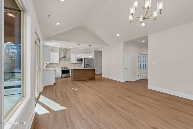 unfurnished living room with sink, high vaulted ceiling, light hardwood / wood-style floors, and a chandelier