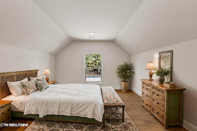 bedroom featuring light wood finished floors, vaulted ceiling, and baseboards