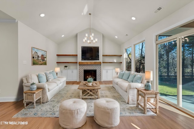 living room with a notable chandelier, a large fireplace, baseboards, wood finished floors, and high vaulted ceiling