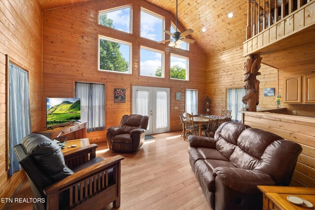 living room featuring wood walls, high vaulted ceiling, wooden ceiling, and light wood-type flooring