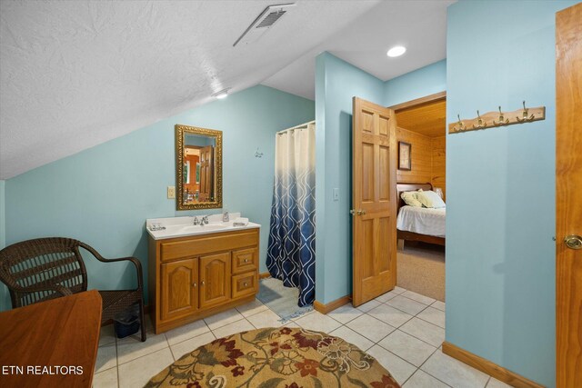 bathroom with tile patterned floors, a textured ceiling, vanity, and lofted ceiling