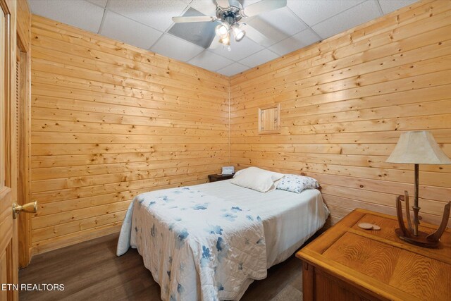 bedroom with a drop ceiling, ceiling fan, and hardwood / wood-style flooring