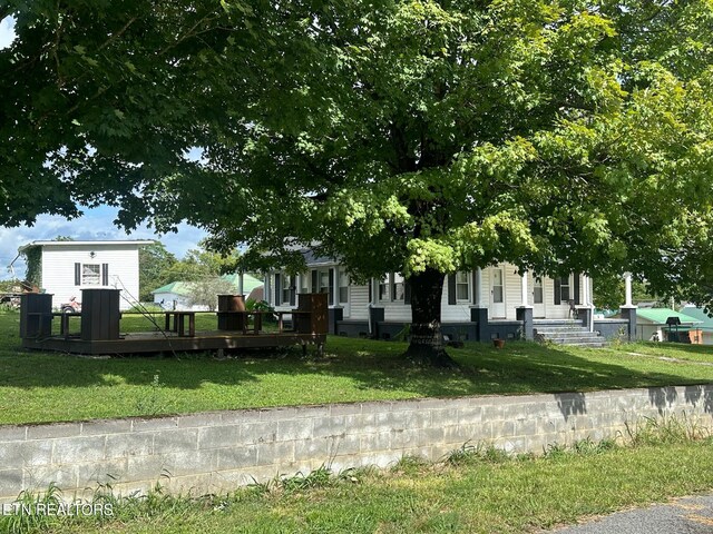 view of front of property with a wooden deck and a front yard