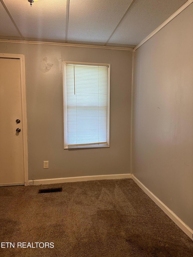 carpeted empty room with a textured ceiling, crown molding, visible vents, and baseboards