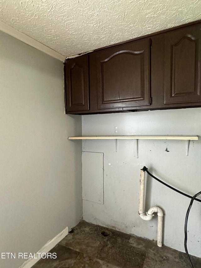 clothes washing area featuring cabinet space and a textured ceiling