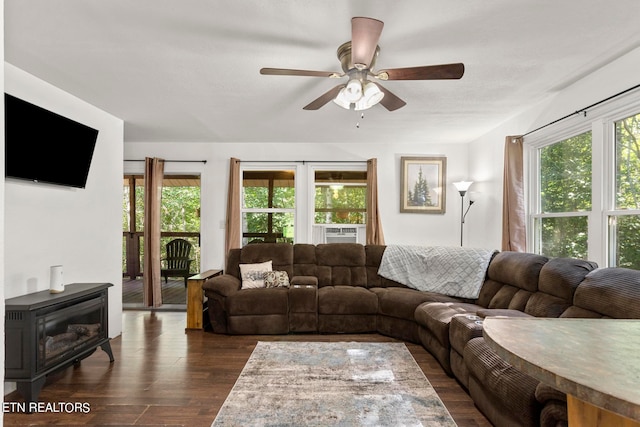 living room featuring ceiling fan, a wood stove, and dark hardwood / wood-style floors