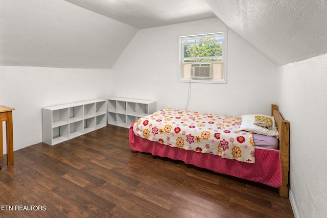 bedroom featuring vaulted ceiling, wood-type flooring, and a textured ceiling