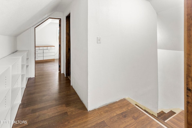 corridor featuring vaulted ceiling and dark wood-type flooring