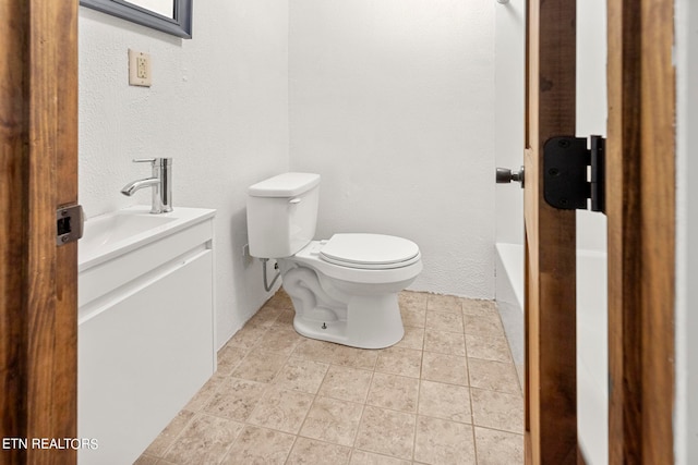 bathroom with a tub, toilet, tile patterned flooring, and vanity