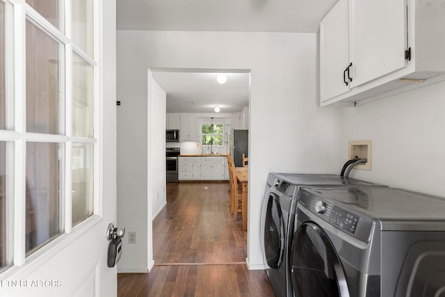 laundry area with washing machine and clothes dryer, cabinets, and dark wood-type flooring