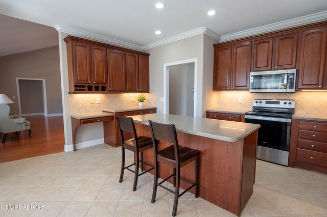 kitchen with appliances with stainless steel finishes, light hardwood / wood-style floors, a kitchen island, and backsplash