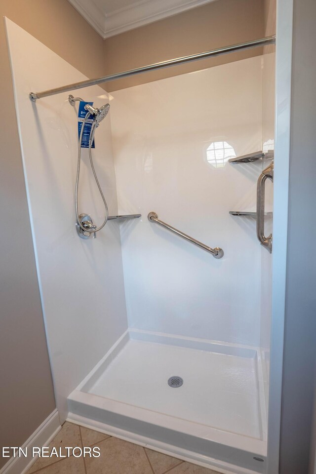 bathroom featuring tile patterned flooring, ornamental molding, and a shower