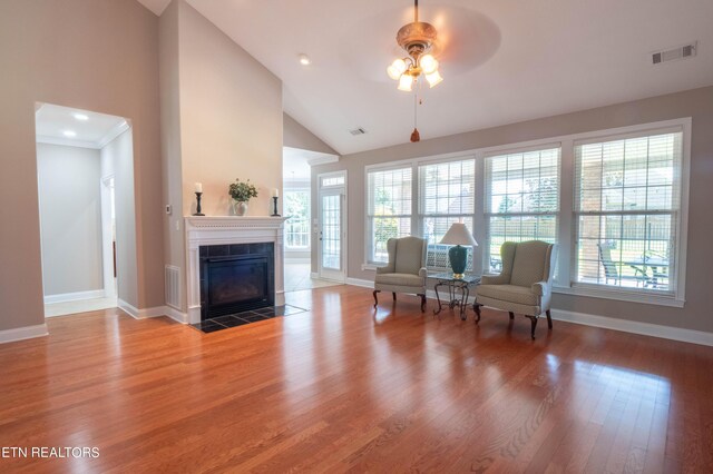 sitting room featuring ceiling fan, high vaulted ceiling, light hardwood / wood-style floors, and a tile fireplace