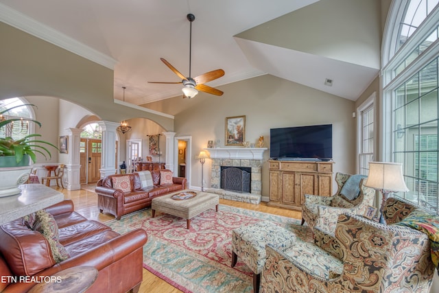 living room with ceiling fan, light hardwood / wood-style floors, ornate columns, a fireplace, and vaulted ceiling