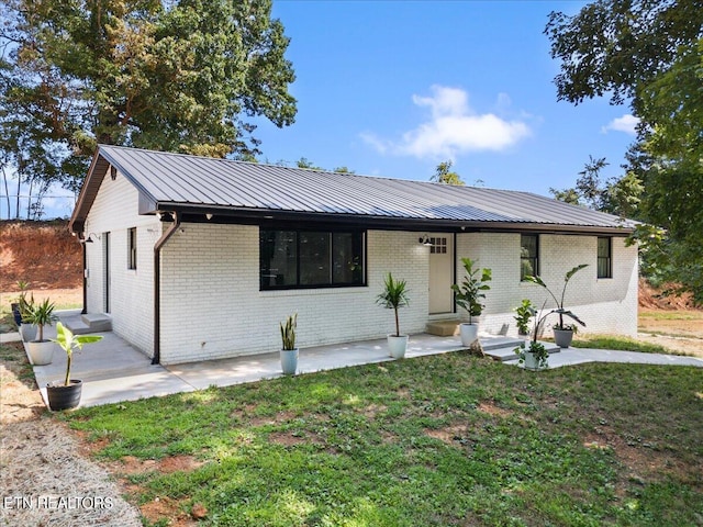 view of front of house with metal roof, brick siding, and a front yard