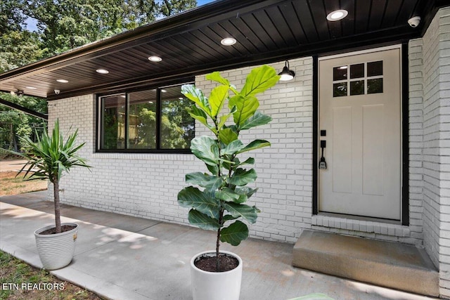 property entrance featuring brick siding and a patio