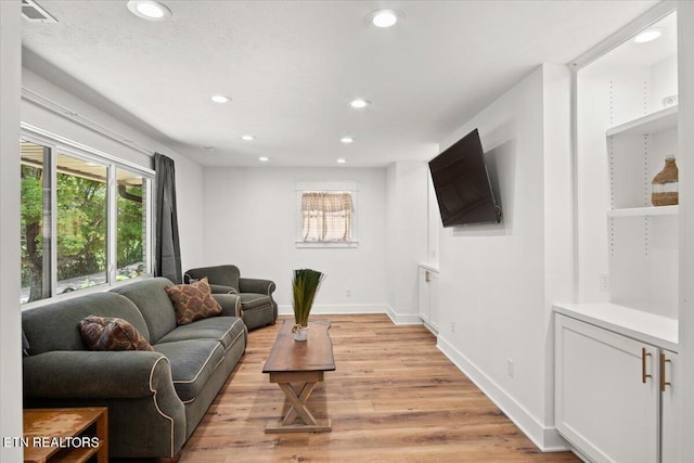 living area featuring recessed lighting, baseboards, and light wood-style floors