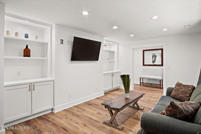 living room with light wood-style flooring, built in shelves, recessed lighting, and baseboards