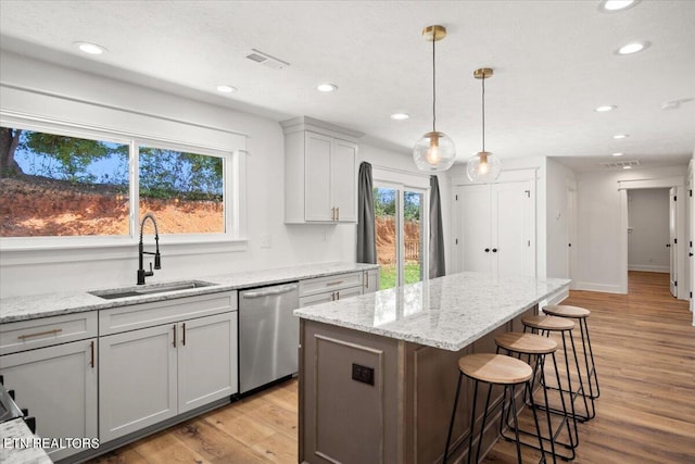 kitchen with a sink, visible vents, light wood-style floors, and stainless steel dishwasher