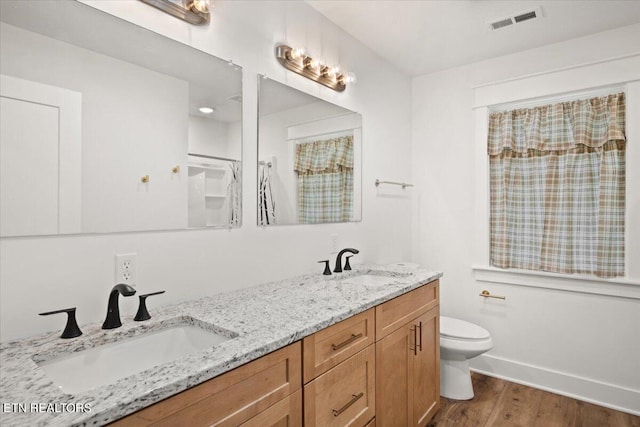 full bath featuring toilet, wood finished floors, visible vents, and a sink