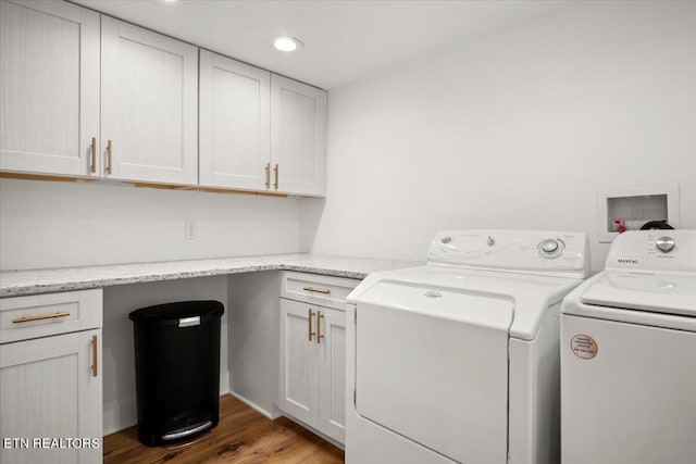 washroom with cabinet space, wood finished floors, and separate washer and dryer