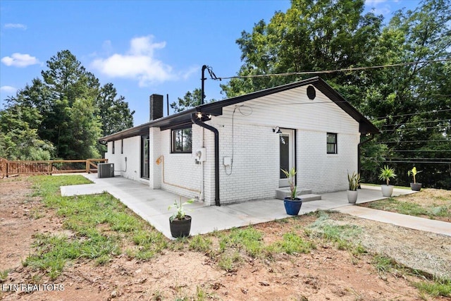 back of property with brick siding, a chimney, a patio, and fence