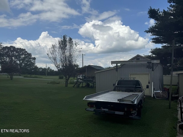 view of yard with a garage and an outbuilding