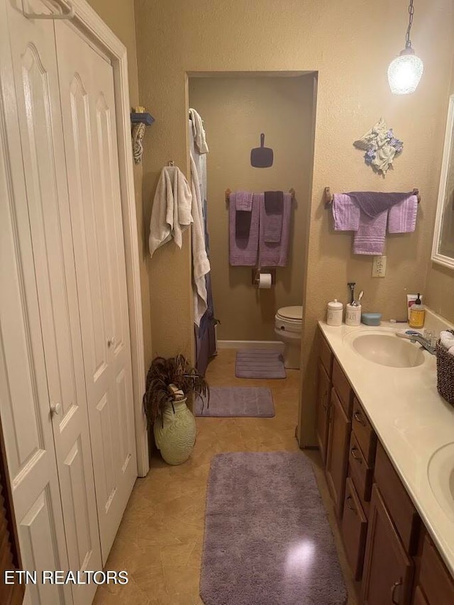 bathroom with dual vanity, toilet, and tile patterned floors