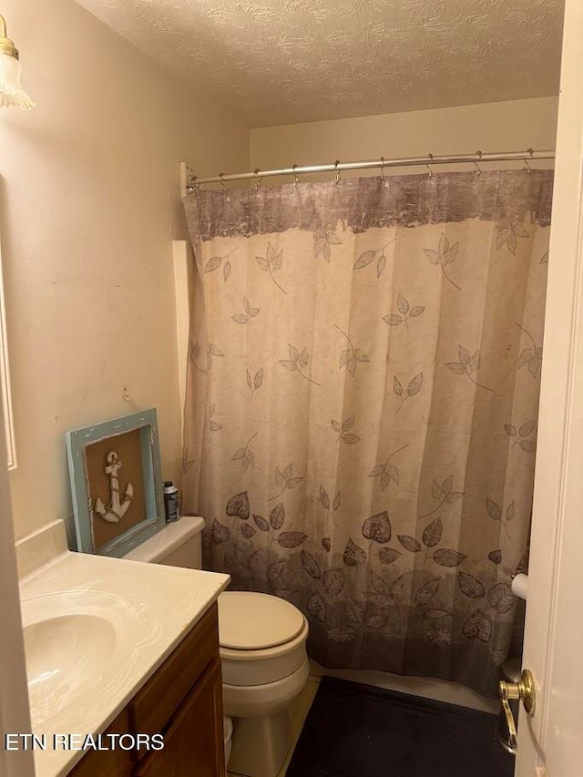 bathroom with a textured ceiling, toilet, and vanity