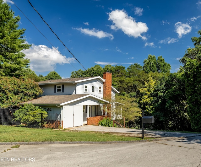 view of front of home featuring a shingled roof, a chimney, a front yard, and fence