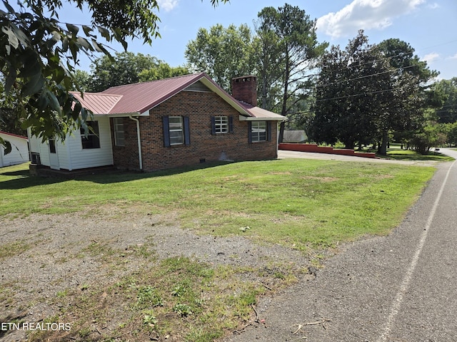 view of home's exterior with brick siding, a yard, a chimney, crawl space, and metal roof