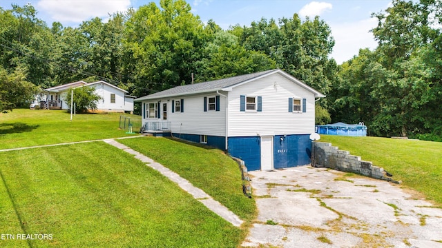 view of front of property featuring a garage, driveway, a swimming pool, and a front yard