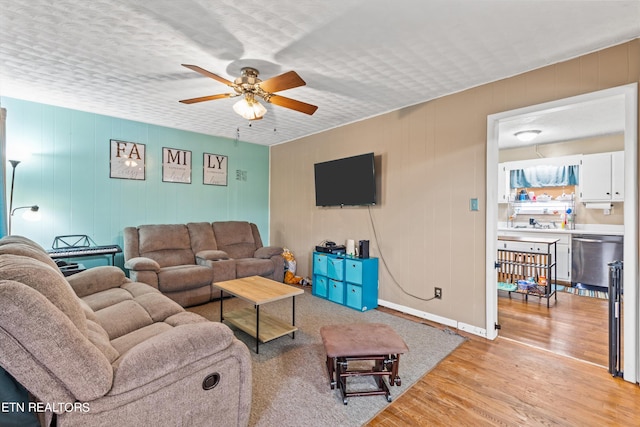 living room featuring ceiling fan, sink, and light hardwood / wood-style floors