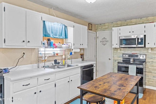 kitchen featuring hardwood / wood-style flooring, sink, white cabinetry, and stainless steel appliances