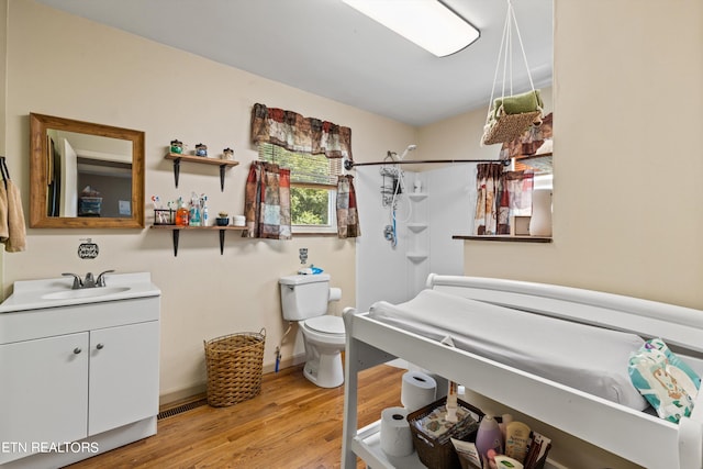 bathroom featuring toilet, vanity, lofted ceiling, and wood-type flooring