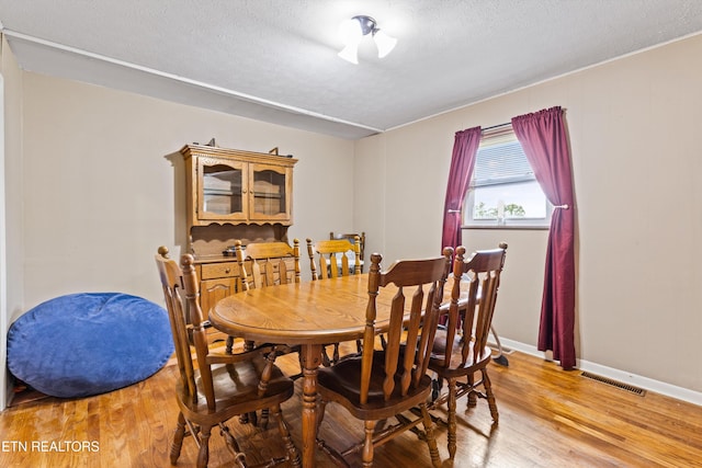 dining area with a textured ceiling and hardwood / wood-style floors