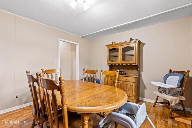 dining space with hardwood / wood-style floors and a textured ceiling