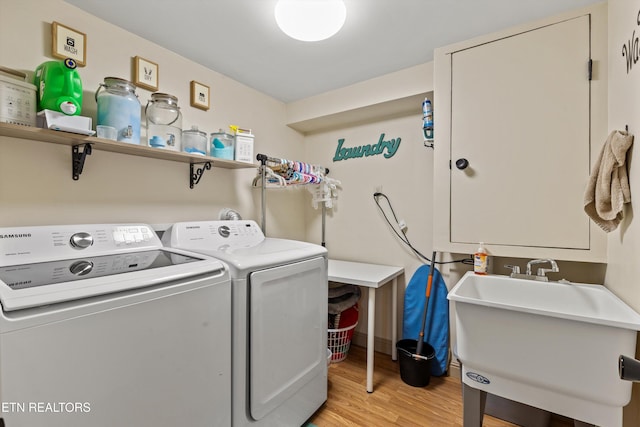 clothes washing area with light hardwood / wood-style floors, sink, and independent washer and dryer