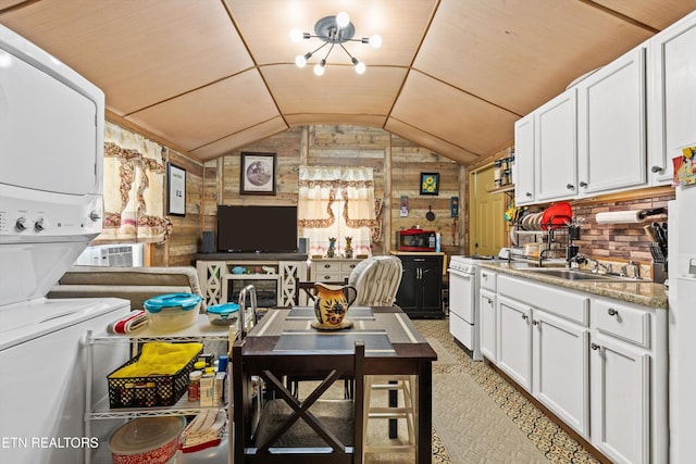 kitchen with wood walls, lofted ceiling, light carpet, white gas stove, and white cabinets