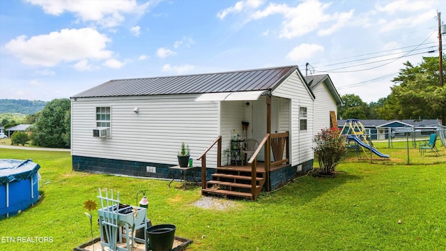 rear view of property with a lawn and a playground