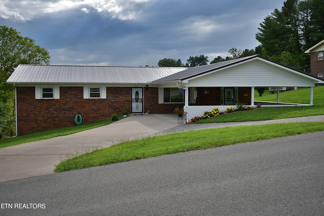 ranch-style house featuring metal roof, brick siding, and a front yard