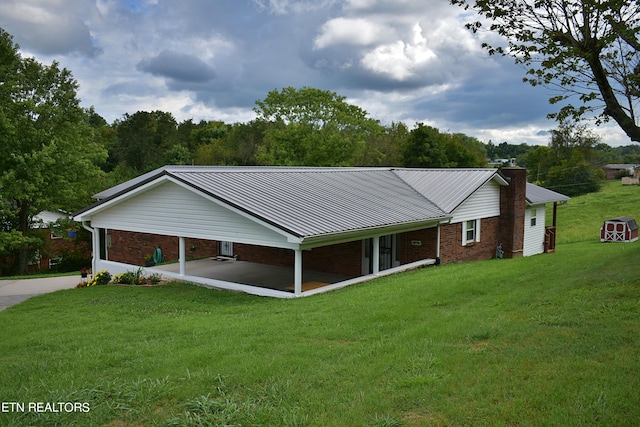 view of front of home with metal roof, an attached carport, brick siding, driveway, and a front yard