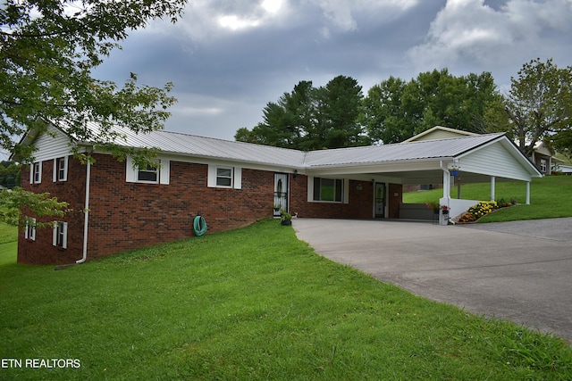 ranch-style house featuring brick siding, metal roof, an attached carport, driveway, and a front lawn