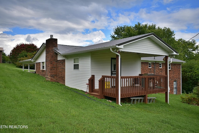 rear view of property featuring metal roof, a yard, brick siding, and a chimney