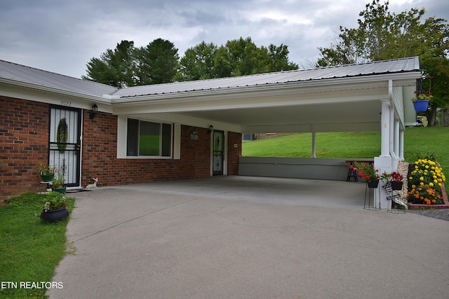 exterior space with metal roof, an attached carport, brick siding, driveway, and a front yard