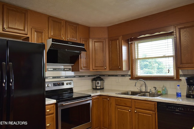 kitchen featuring black appliances, extractor fan, a sink, and brown cabinetry