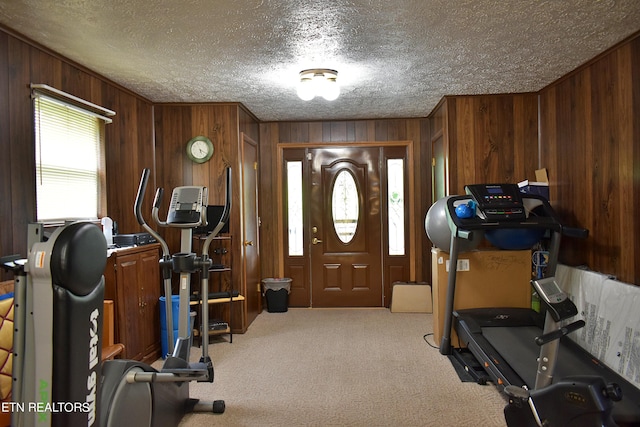 exercise room featuring a textured ceiling, wood walls, and carpet flooring